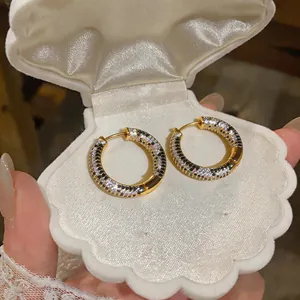 Macro view of luxury 18K gold plated hoop earrings with black and white zircon in shell box