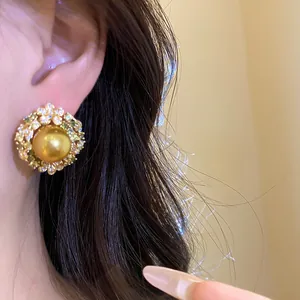 Detailed view of golden pearl stud earring featuring a sparkling zircon floral halo design