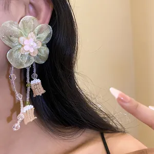 Vista detallada de los pendientes de flores de gasa verde con flecos de cuentas