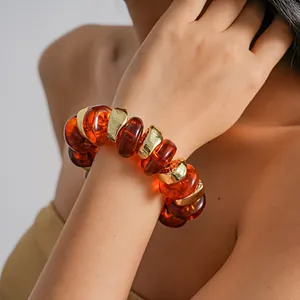 Detailed view of a retro amber acrylic irregular bead bracelet on model's wrist.