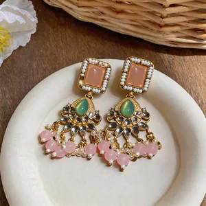 Macro view of vintage style earrings with pink resin beads and intricate gold details.