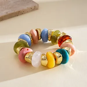 Close-up of colorful irregular acrylic beads and gold spacers on an elastic bracelet