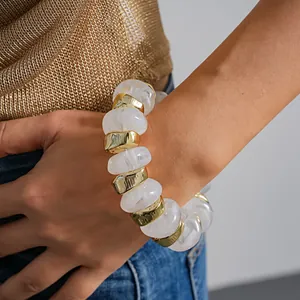 Close-up of a chunky white marble acrylic and gold geometric bead elastic bracelet.