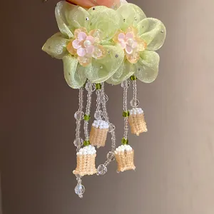 Detalle de pendientes de flores de gasa verde claro con perlas y borlas de cuentas