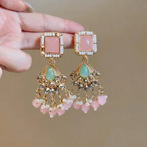 Detailed view of vintage style gold-tone earrings with pink and green resin stones.