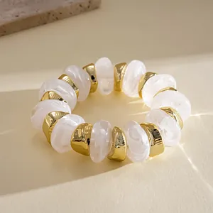 Detailed macro view of white marbled acrylic and gold geometric beaded bracelet.