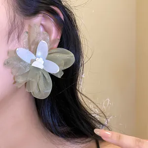 Detalle de primer plano de elegantes pendientes de flor de gasa para mujer puestos en la oreja