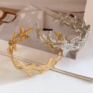 Detailed view of gold and silver metal starfish open cuff bracelets in a minimalist design.