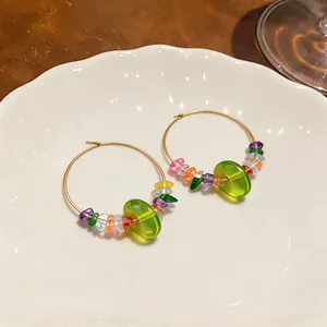 Detailed view of colorful resin beaded gold hoop earrings on white ceramic plate