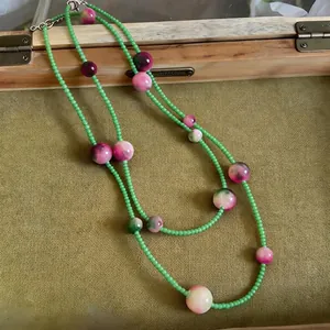 Long forest style beaded necklace featuring green seed beads and pink marbled cat's eye stones