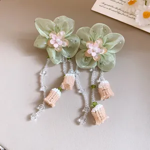 Vista detallada de los pendientes de flores de gasa con elegantes borlas de cuentas y plata.
