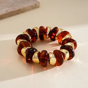 Detailed macro view of amber acrylic beads and golden spacers on a textured surface