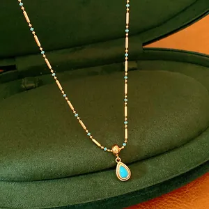 Vue macro détaillée d'un collier goutte d'eau plaqué or 18 carats avec perles turquoises.