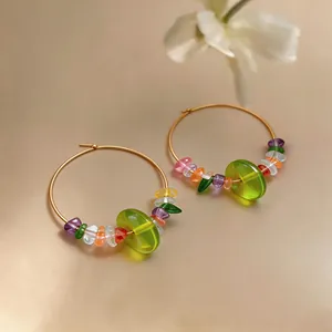 Close-up of vibrant translucent resin beads and stones on elegant gold hoop earrings