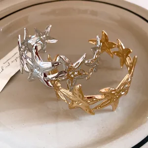 Detailed macro view of gold and silver starfish open metal bangles on a ceramic plate