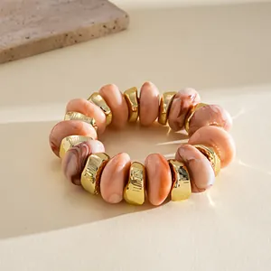 Close-up detail of peach marble acrylic and gold irregular geometric beaded elastic bracelet