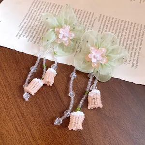 Vista detallada que muestra la textura de pendientes de flores de gasa con borlas de perlas.