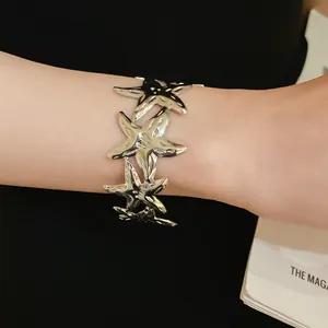 Close-up of a silver-toned metal starfish cuff bracelet on a wrist with reflective finish