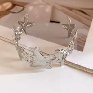 Close-up of silver metal starfish-shaped open cuff bracelet with glossy finish.