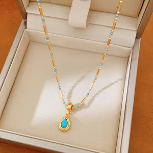 Gros plan d'un collier plaqué or 18 carats avec pendentif goutte bleue.