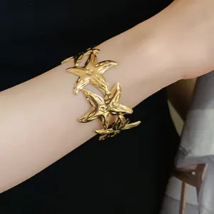 Detailed close-up showing a fashionable gold-toned starfish-shaped metal cuff bracelet on a wrist