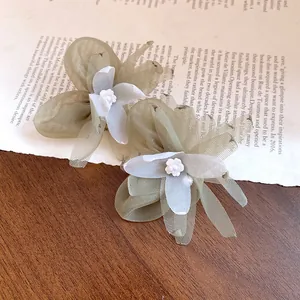 Detalle de elegantes pendientes de flores de gasa y perlas sobre fondo de periódico