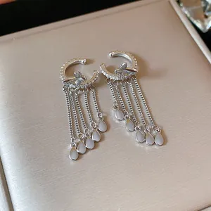 Detailed macro view of silver zircon butterfly tassel ear clips on a jewelry box lid.
