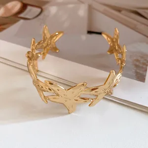 Close-up of gold metal starfish cuff bracelet detail against a minimalist background