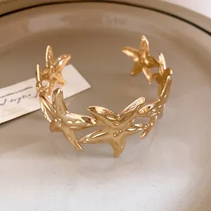 Close-up view of an elegant gold starfish open cuff bracelet with a polished metal finish