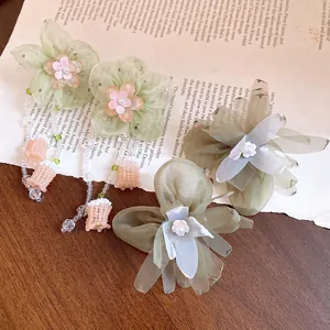 Primer plano de pendientes de flores de gasa con perlas y borlas de cuentas finas.