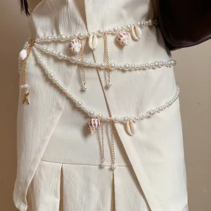 Close-up of a elegant pearl waist chain with sea shells and starfish on a white dress
