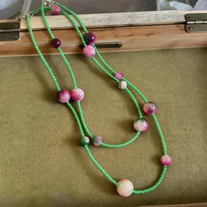 Close-up of Mori style long necklace with green beads and marbled cat's eye stones.