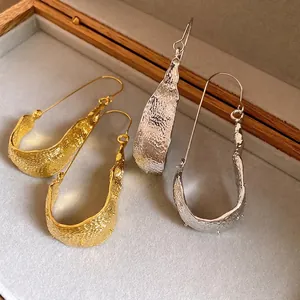 Elegant minimalist U-shaped textured metal drop earrings in gold and silver finish