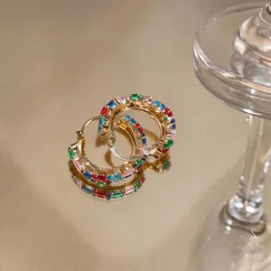 Macro view of colorful baguette-cut zircon hoop earrings with a premium gold finish