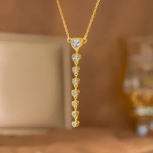 Vista detallada de un elegante collar dorado en Y con borlas de corazones y zirconitas