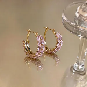 Macro detail of pink marquise zircon stones on gold-plated wheat ear hoop earrings.