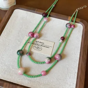 Macro detail of forest style double-layered beaded necklace with pink cat-eye stones.