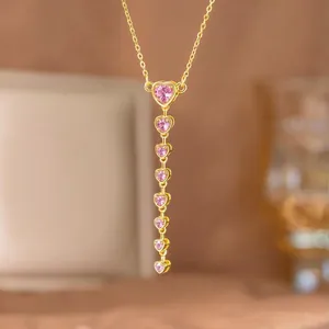 Primer plano de collar en Y dorado con circonitas rosas en forma de corazón