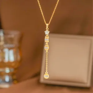 Detalle macro de un collar en forma de Y dorado con brillantes dijes de estrellas y geométricos
