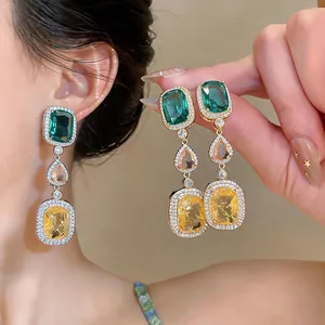 Close-up detail of vintage emerald green and yellow zircon drop earrings with crystal pavé