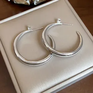 Close-up of silver-plated hoop earrings with sparkling zircon studs on a luxury box.