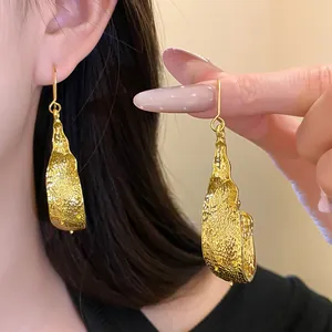 Detailed view of gold textured irregular U-shaped drop earrings for a luxury look.