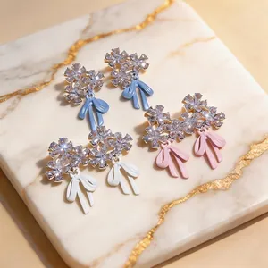 Pendientes de flores con cristales y lazos de esmalte sobre fondo de mármol elegante