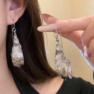 Detailed view of elegant silver U-shaped pendant earrings featuring organic molten texture.