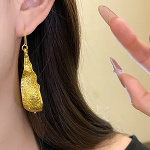 Close-up detail of a minimalist golden U-shaped earring with elegant textured finish