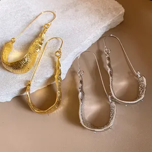Detailed view of textured U-shaped metal drop earrings in gold and silver color options