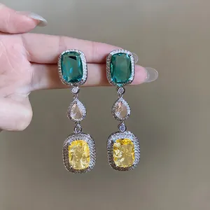 Detailed view of vintage silver needle drop earrings with emerald and yellow zircons