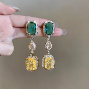 Close-up of vintage square drop earrings with green, peach and yellow zircons