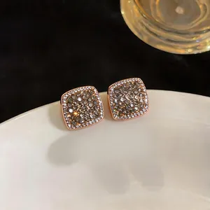 Close-up detail of rose gold square stud earrings paved with shimmering grey and clear crystals