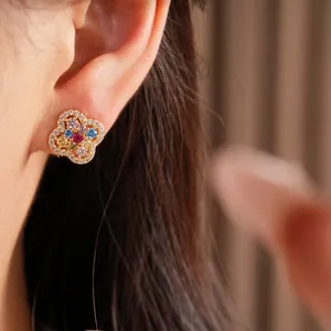 Detailed view of 14k gold-plated clover flower stud earring with colorful zircons on ear